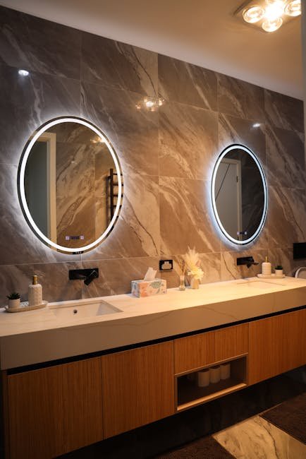 Elegant bathroom interior featuring a double vanity with circular backlit mirrors, sleek design.